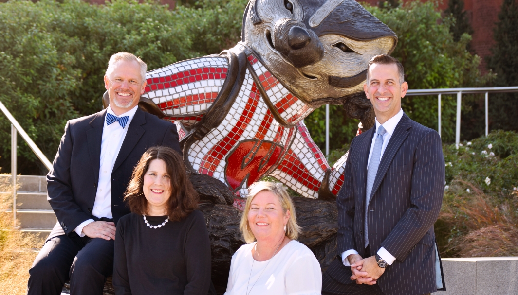 the members of the 1848 team smiling and standing in front of a statue of the University of Wisconsin Bucky Badger mascot